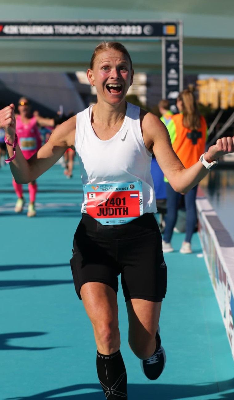 Judith hardlopend over de finish tijdens een hardloop evenement